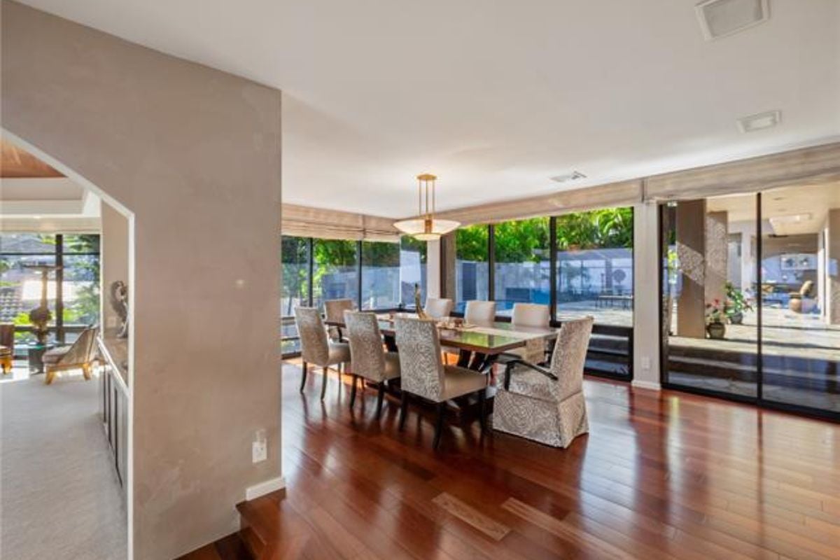 A dining room with windows and a dining table surrounded by chairs.