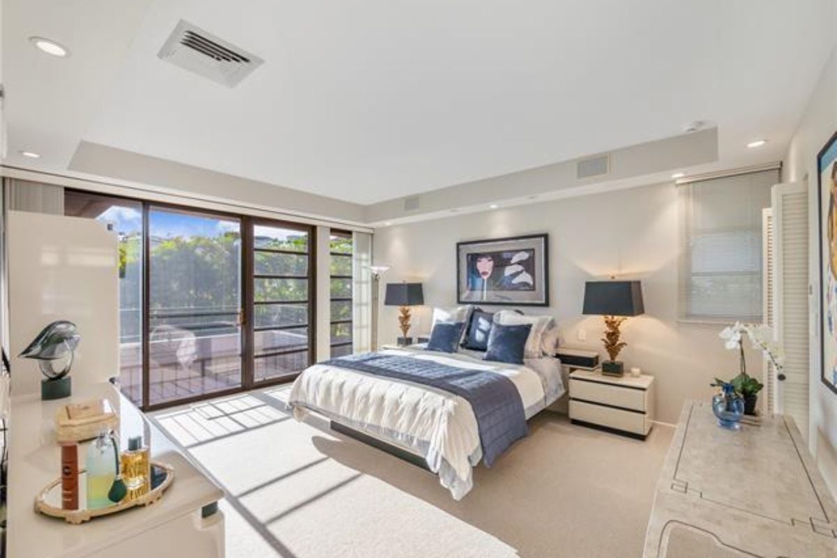 A bedroom with a bed, painting, nightstands, and a countertop.