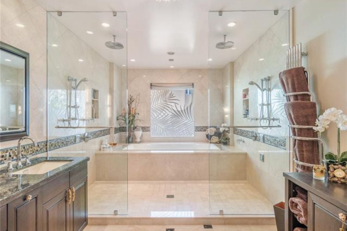A bathroom with a vanity, mirror, cabinets, and a bathtub.