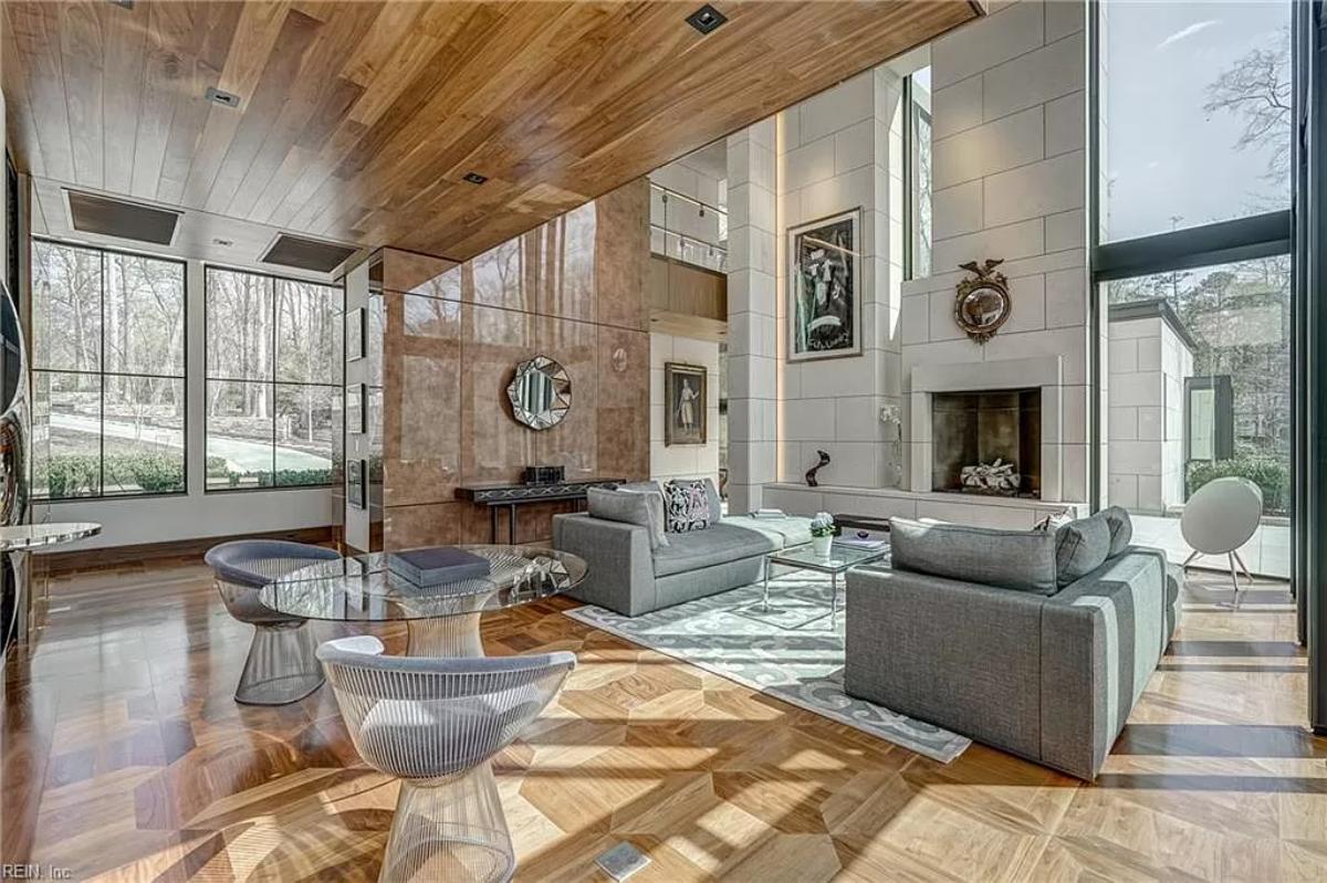 Living room with couches, a fireplace, glass walls and hardwood floors.