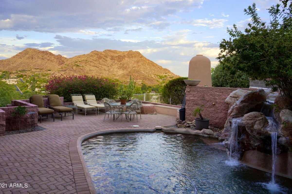 A patio with chairs, a coffee table, a pond, and a waterfall.