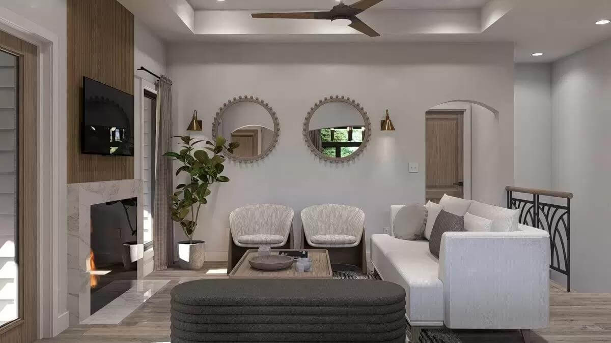 Great room with contemporary seats, round mirrors, and a fireplace with a TV on top.