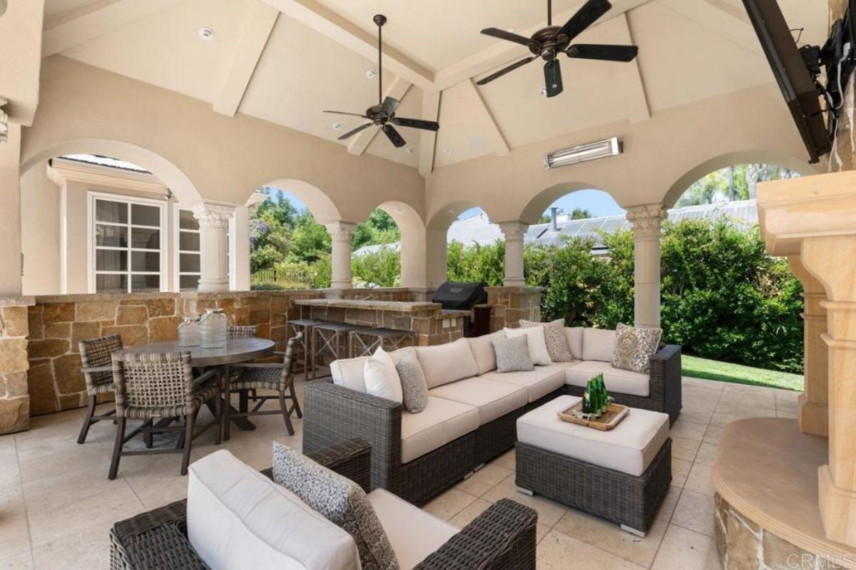 An outdoor living area with a ceiling fan, living space, dining table, and kitchen.