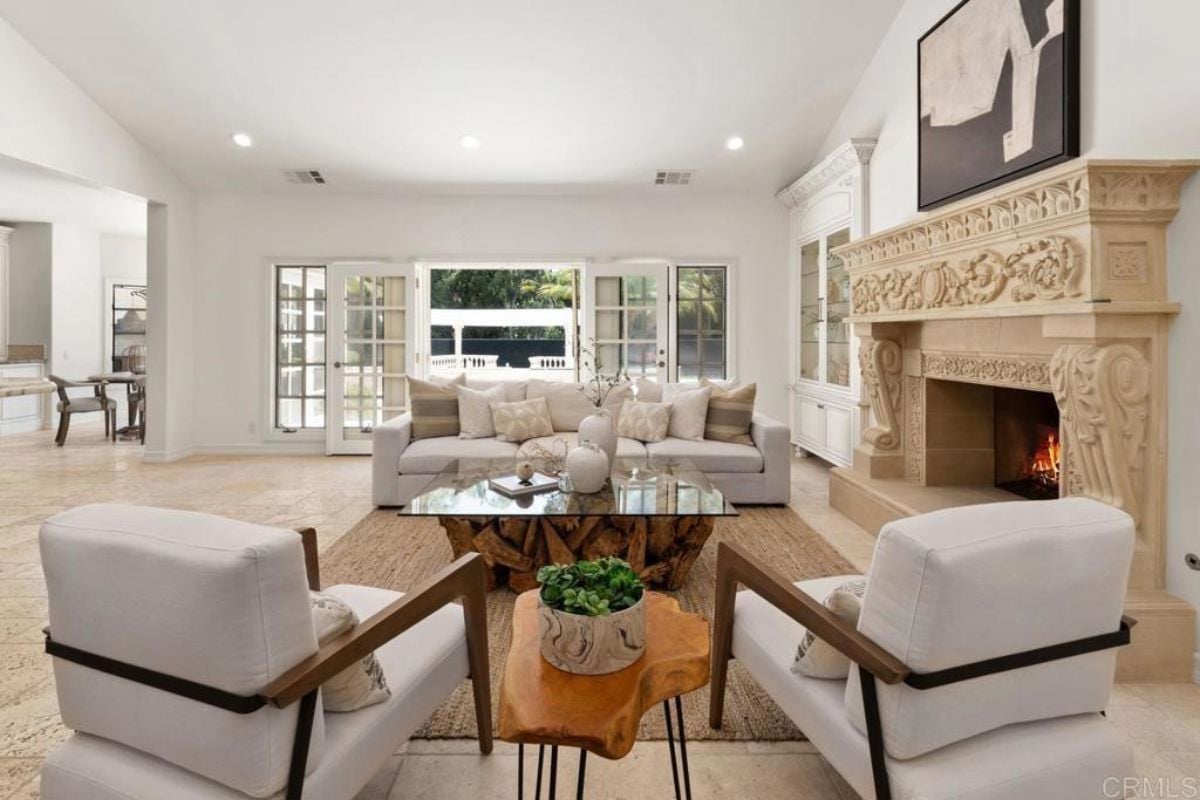 A living room with a painting, fireplace, glass center table, chairs, and a couch.