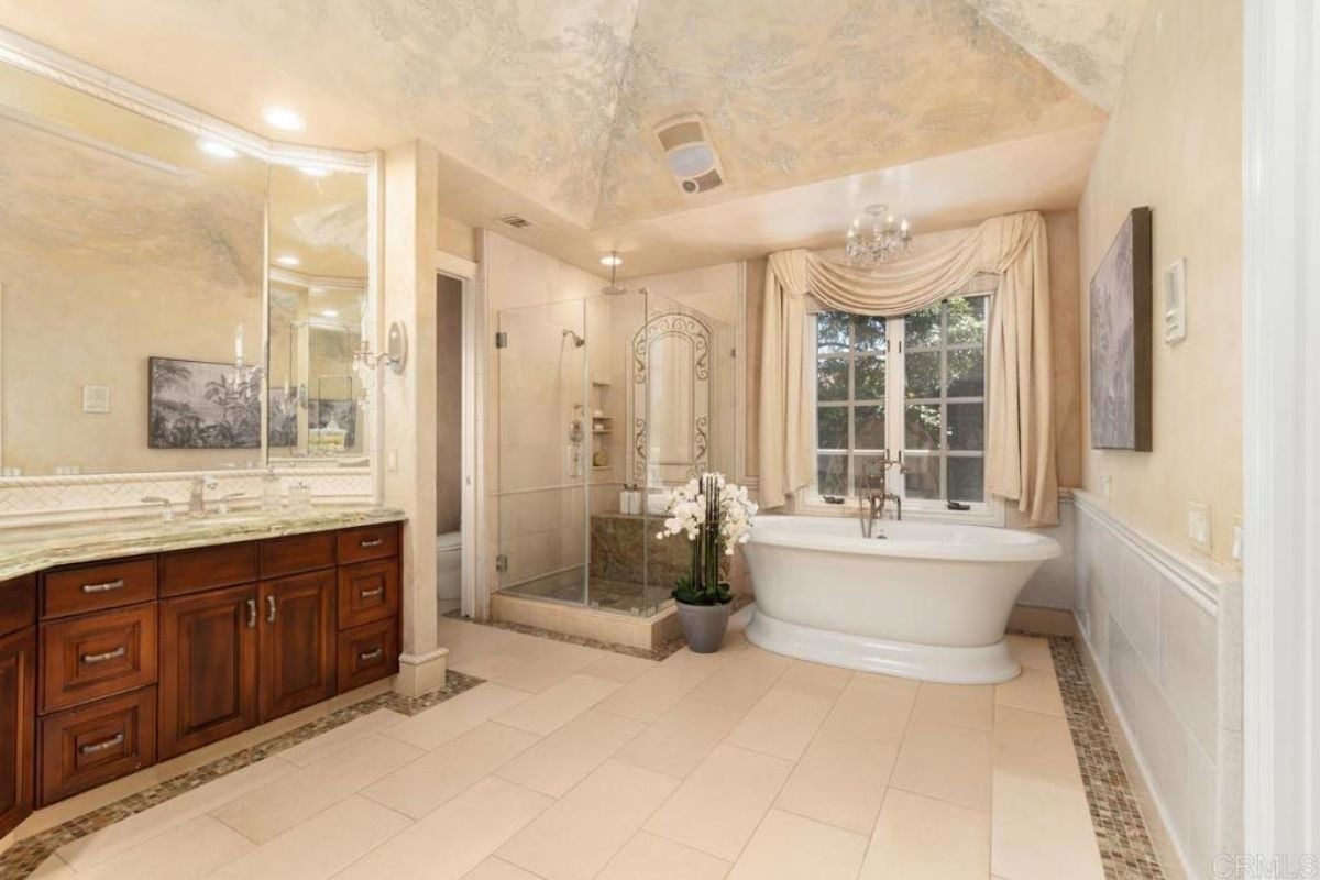 A bathroom with a window, vanity, mirror, cabinet, shower room, and bathtub.