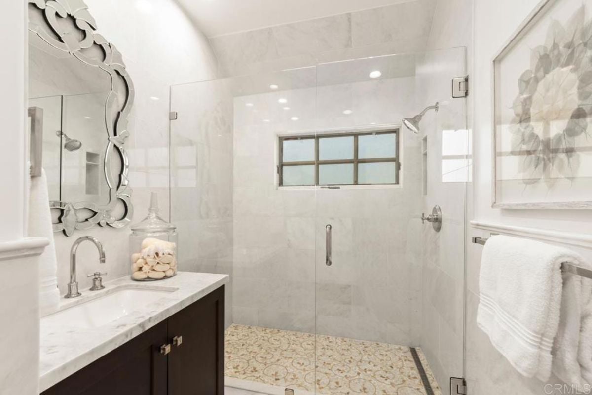 A bathroom with a vanity, mirror, and shower.
