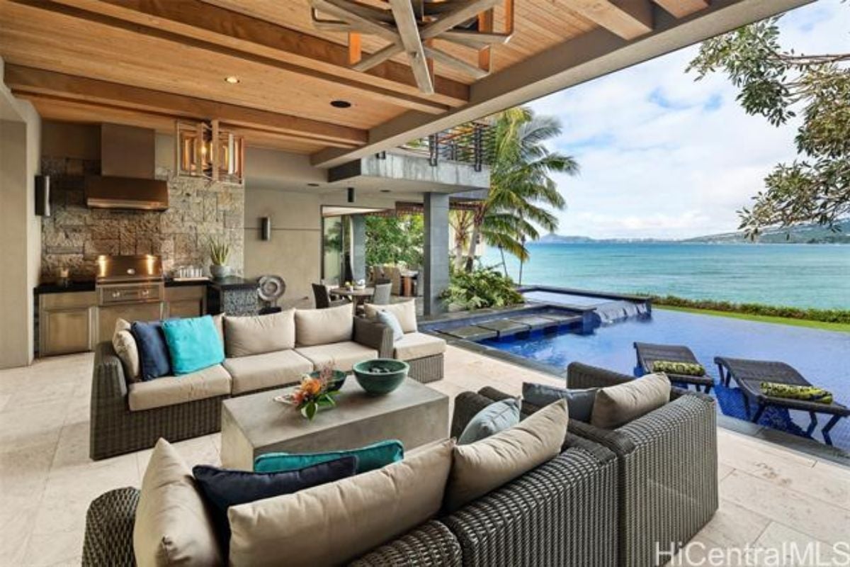 An outdoor living space with couches, a center table, and a kitchen.