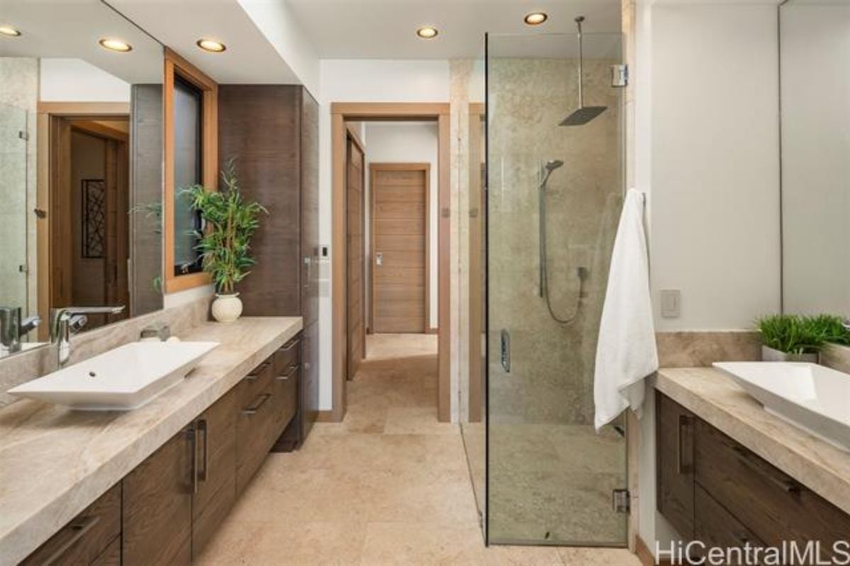 A bathroom with vanities, mirror, shower room, and cabinets.