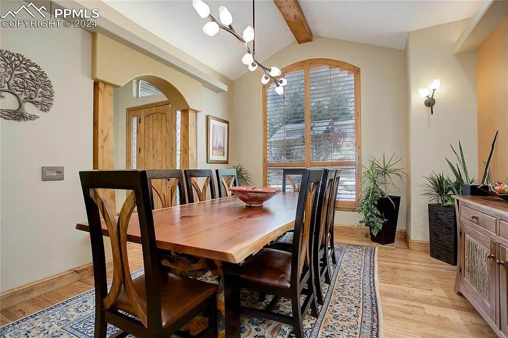 Dining room with a rectangular dining set and a cathedral ceiling lined by an exposed beam.