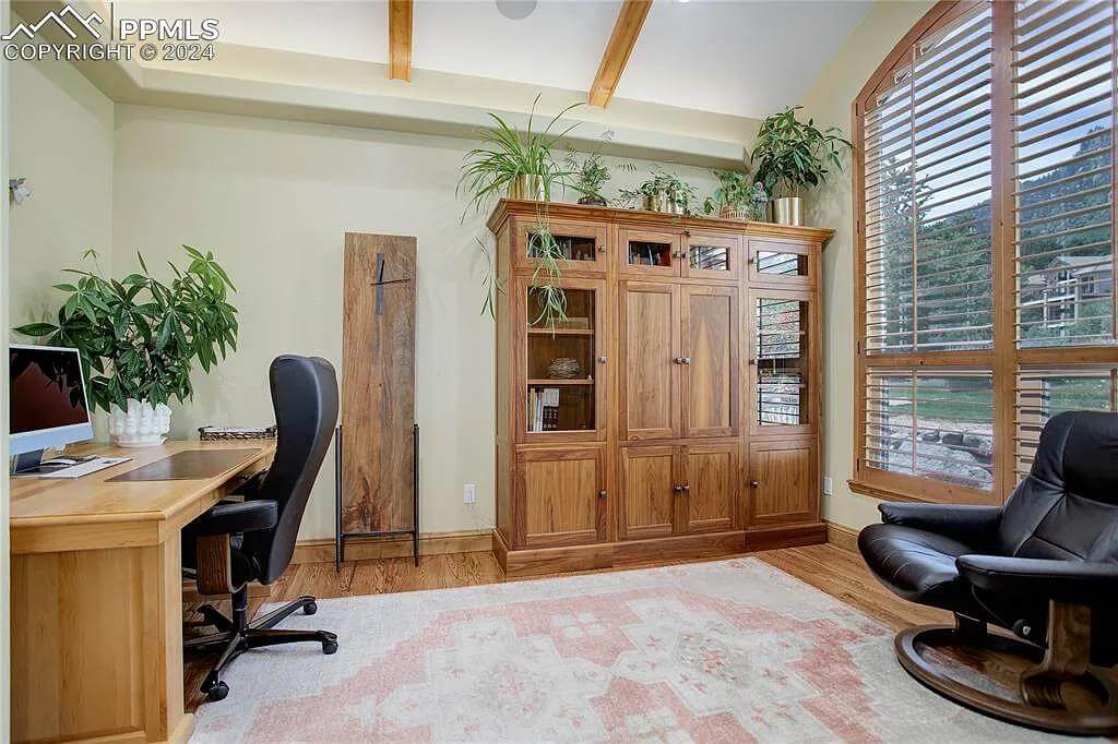 Office with leather chairs, a wooden desk, and a matching cabinet under the beamed ceiling.