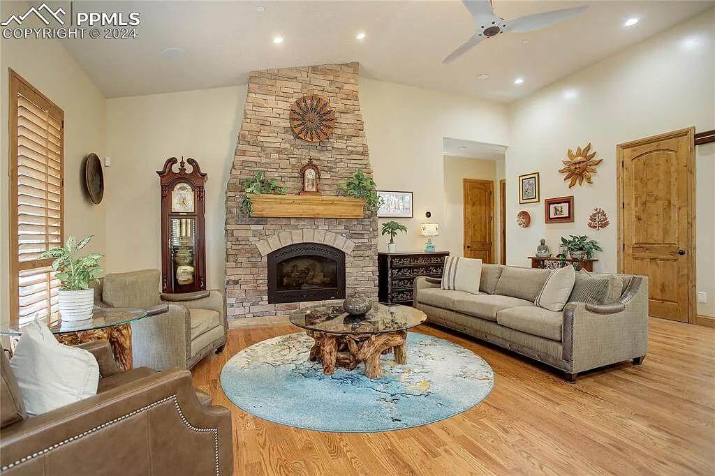 Living room with taupe seats, a stump coffee table, and a stone fireplace.