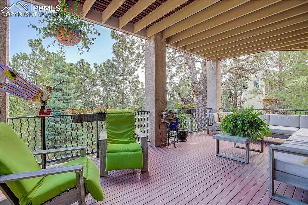 Covered deck with cushioned chairs and a beamed ceiling.