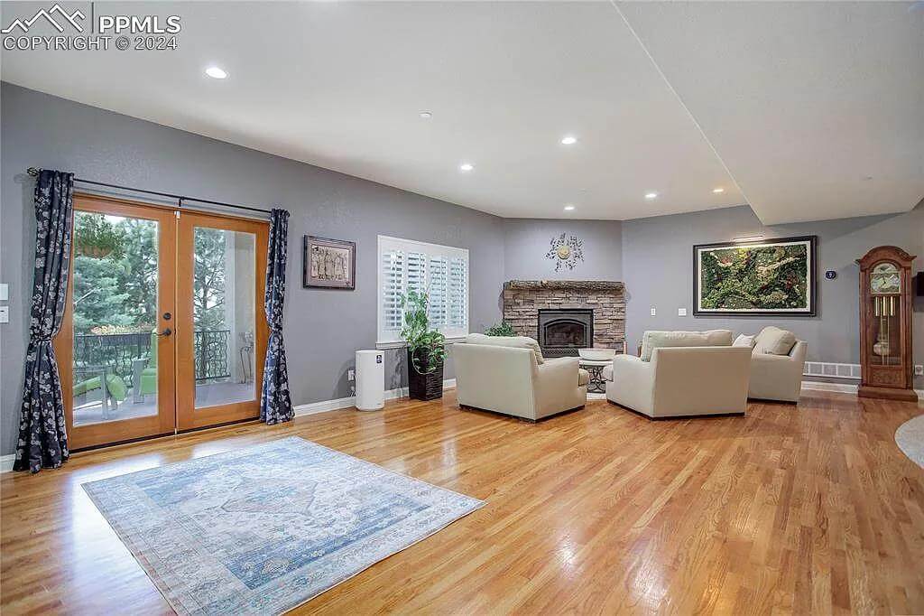 Family room with a stone fireplace, beige sofas, and a French door that opens to a patio.