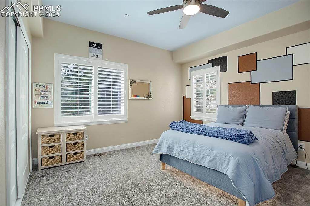 Bedroom with an upholstered bed and louvered windows.