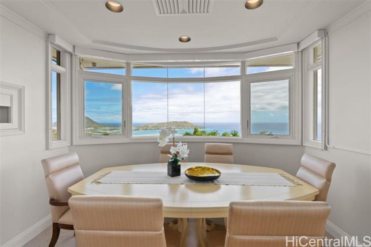 A dining room with a window and a dining table surrounded by chairs.