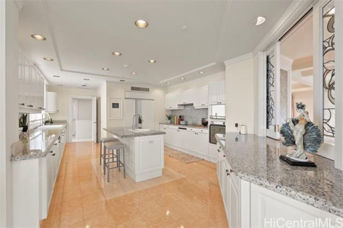 A kitchen with a center island, stools, countertops, and cabinets.