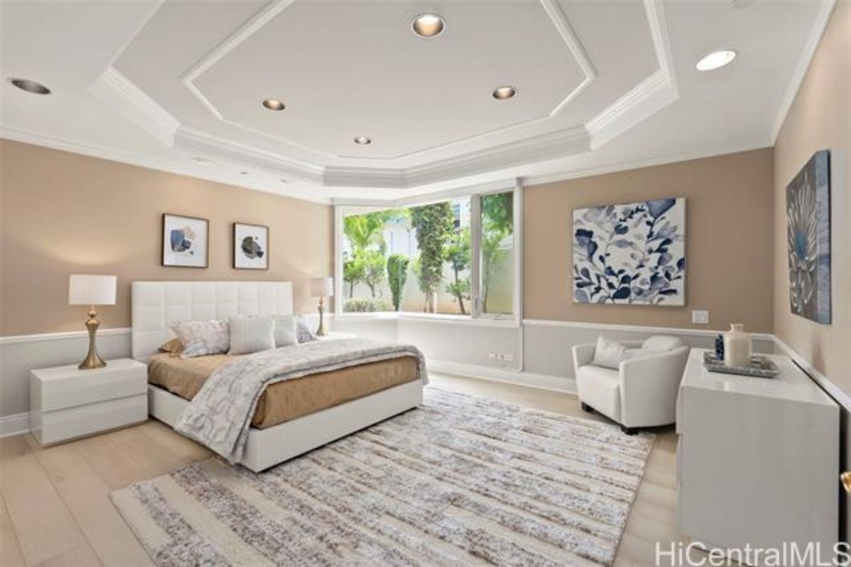 A bedroom with a bed, rug, nightstands, window, paintings, and a cabinet.