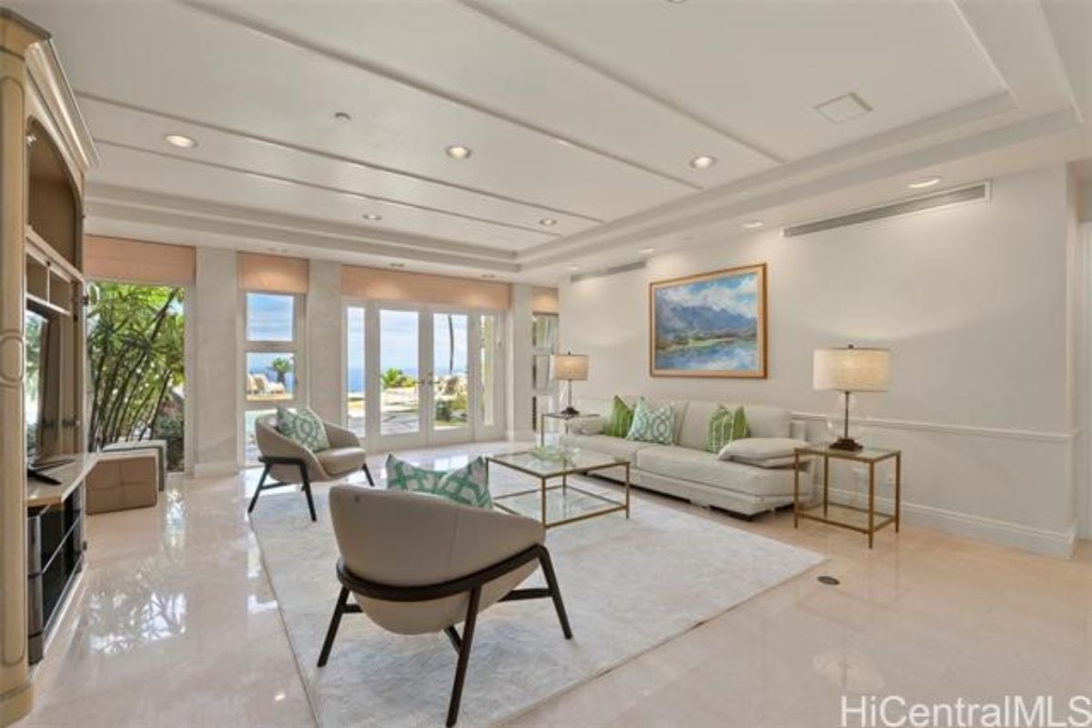 A family room with a painting, rug, chairs, and a couch.