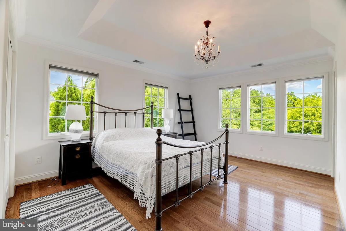 Bedroom with hardwood floors, a chandelier and glass windows.