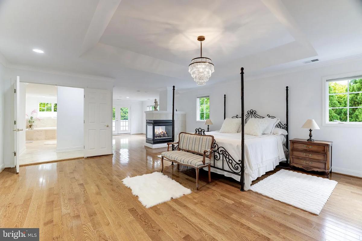 Bedroom with hardwood floors, a chandelier and a fireplace.