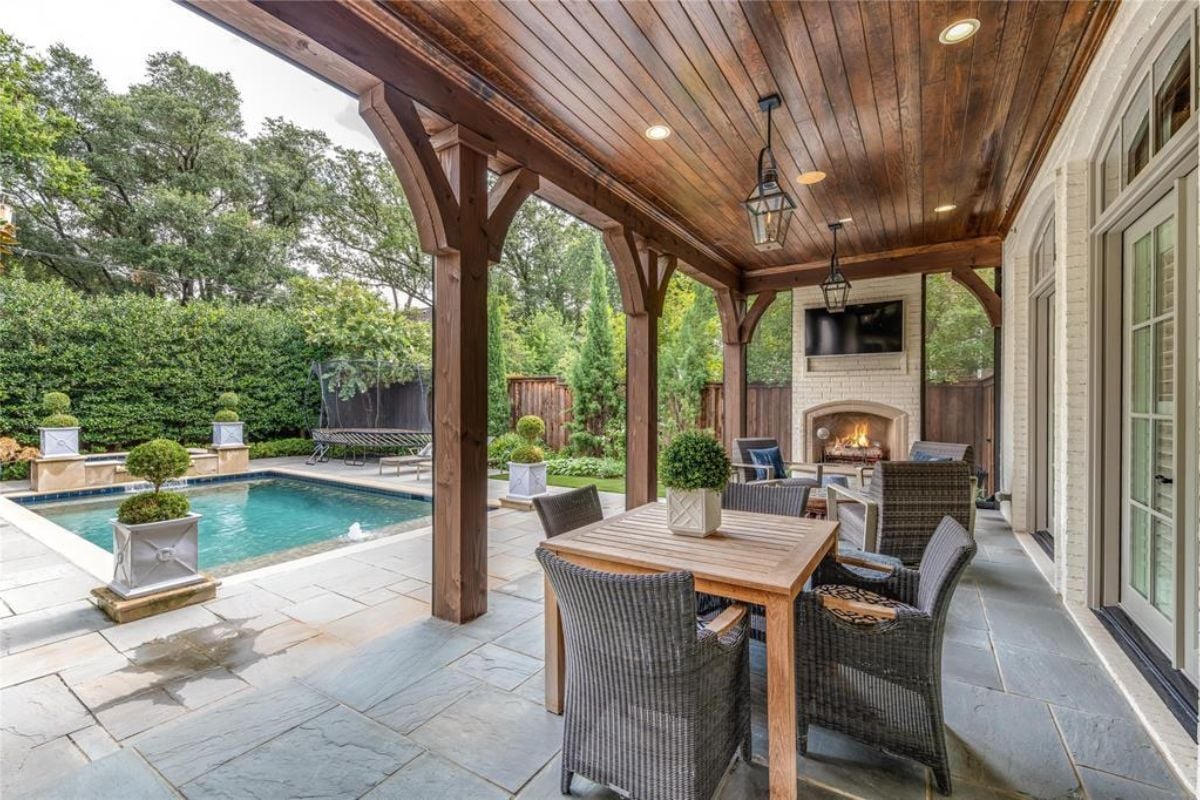 A back porch with a TV, a fireplace, chairs, and a table.