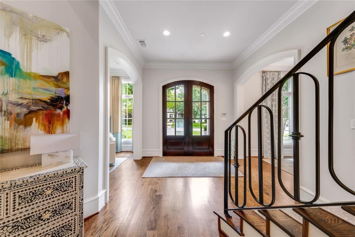 A foyer with a painting, wooden flooring, and a rug.