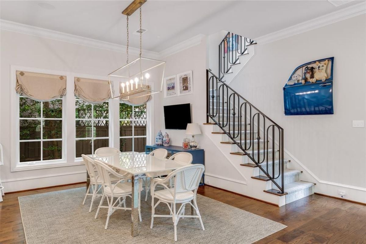 A dining area with a TV, a window, a cabinet, and a dining table surrounded by chairs.