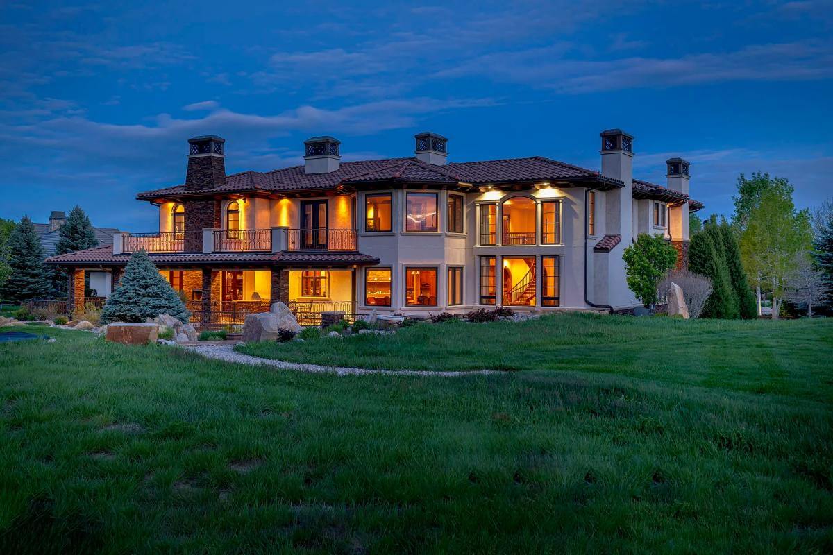 Rear view of the 5-bedroom mansion with multiple chimneys, stacked porches, and a multitude of windows.