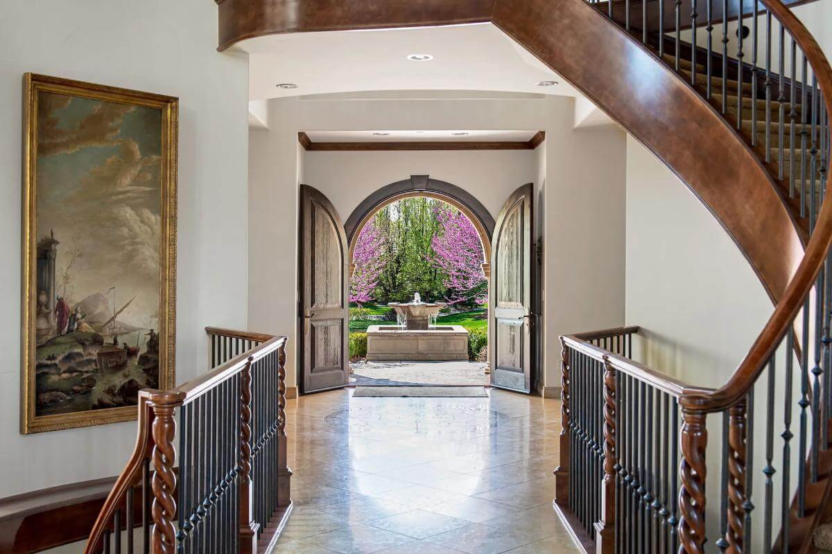 Foyer with an arched French door and wooden railings.