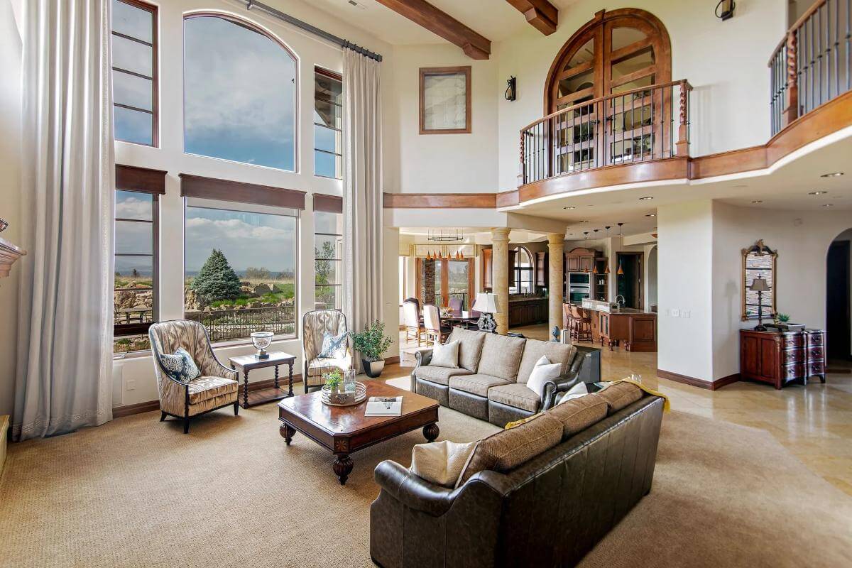 Living room with leather sofas, huge windows, and a tall ceiling adorned by exposed beams.