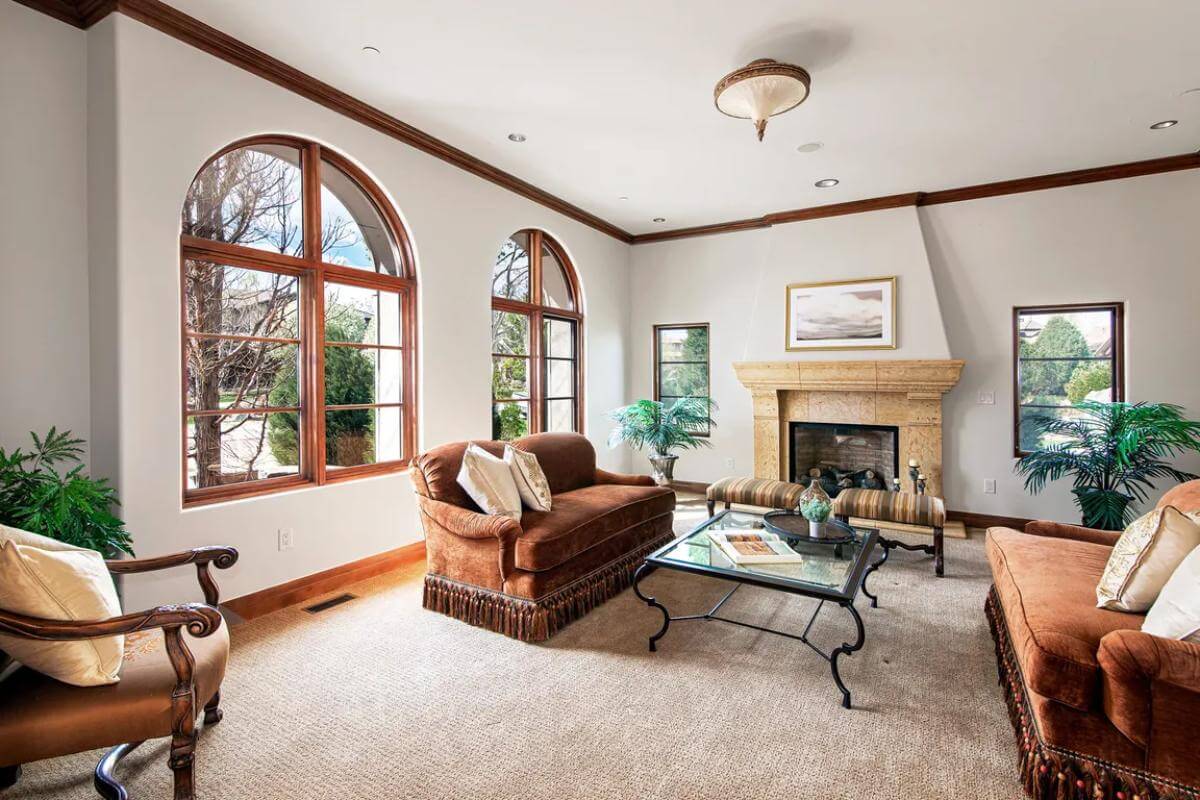 Family room with brown sofas, a fireplace, and arched windows.