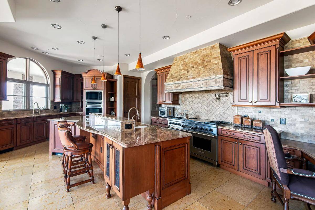 Kitchen with wooden cabinets and a matching island topped by small pendants.