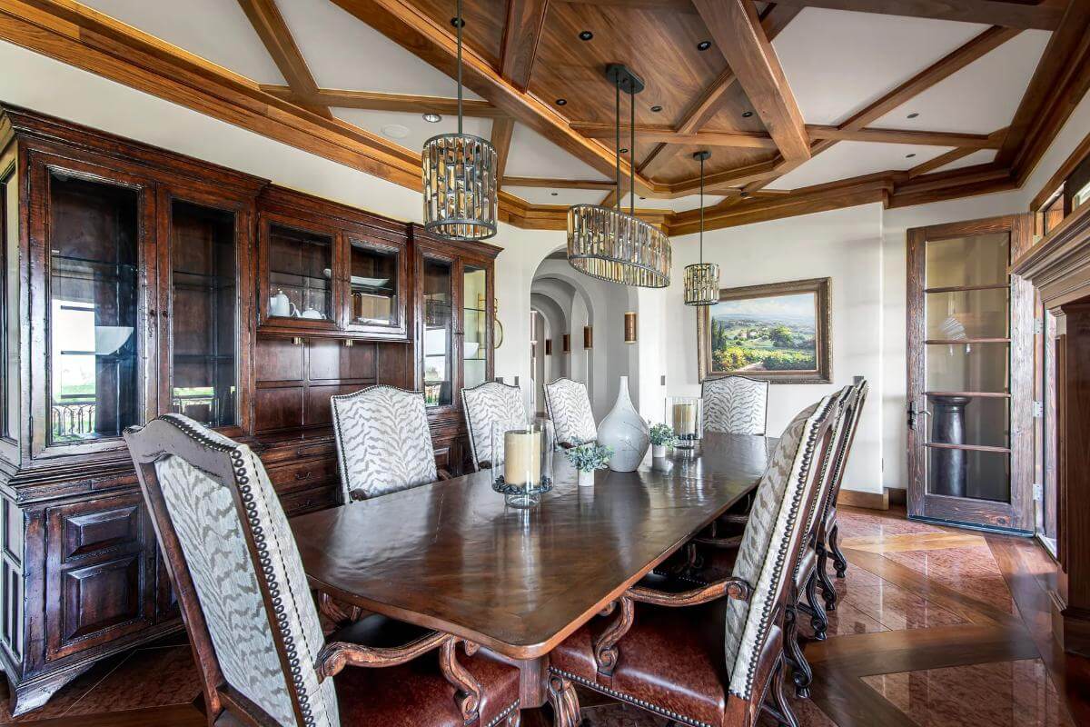 Dining room with a display cabinet and a rectangular dining set illuminated by wrought iron chandeliers.