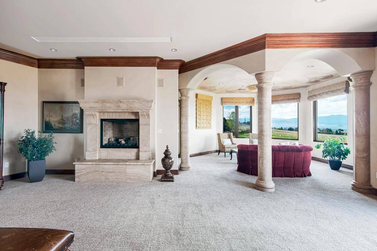 Primary sitting area with a fireplace, round columns, and a bay window.