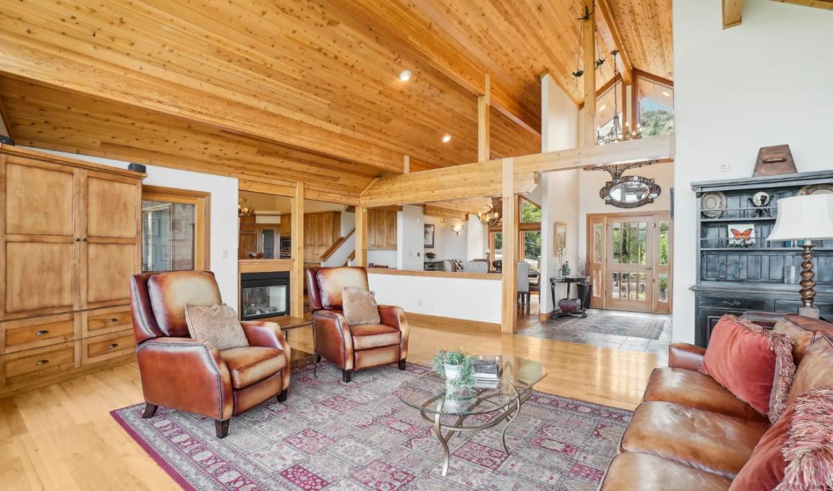 Living room with couches and hardwood flooring.