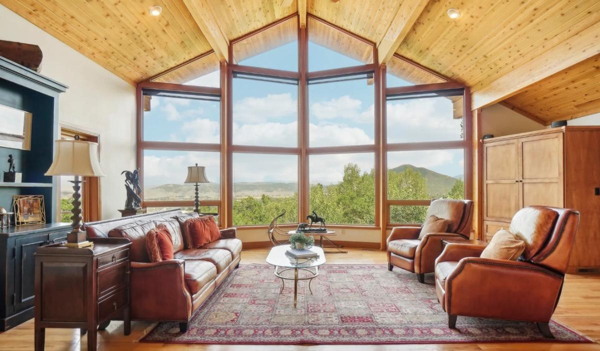 Living room with couches, large glass windows and hardwood flooring.