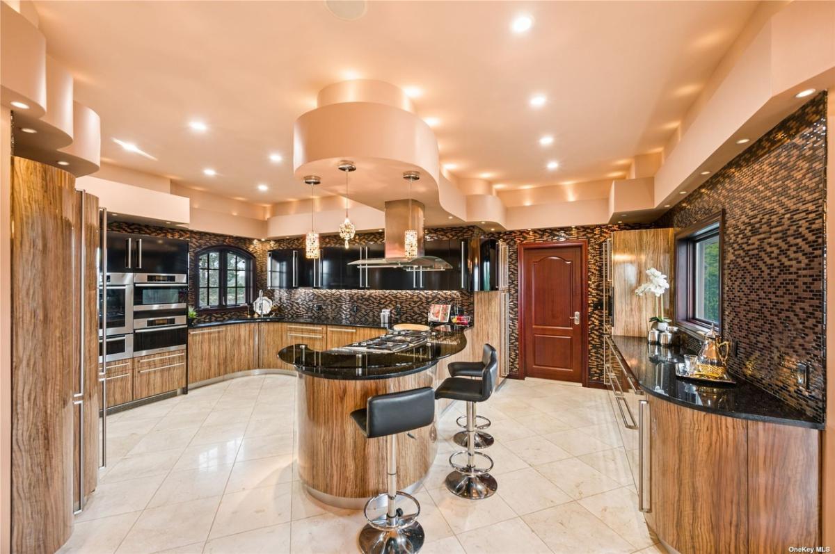 Kitchen with stainless-steel appliances, counter breakfast bar and custom lighting.