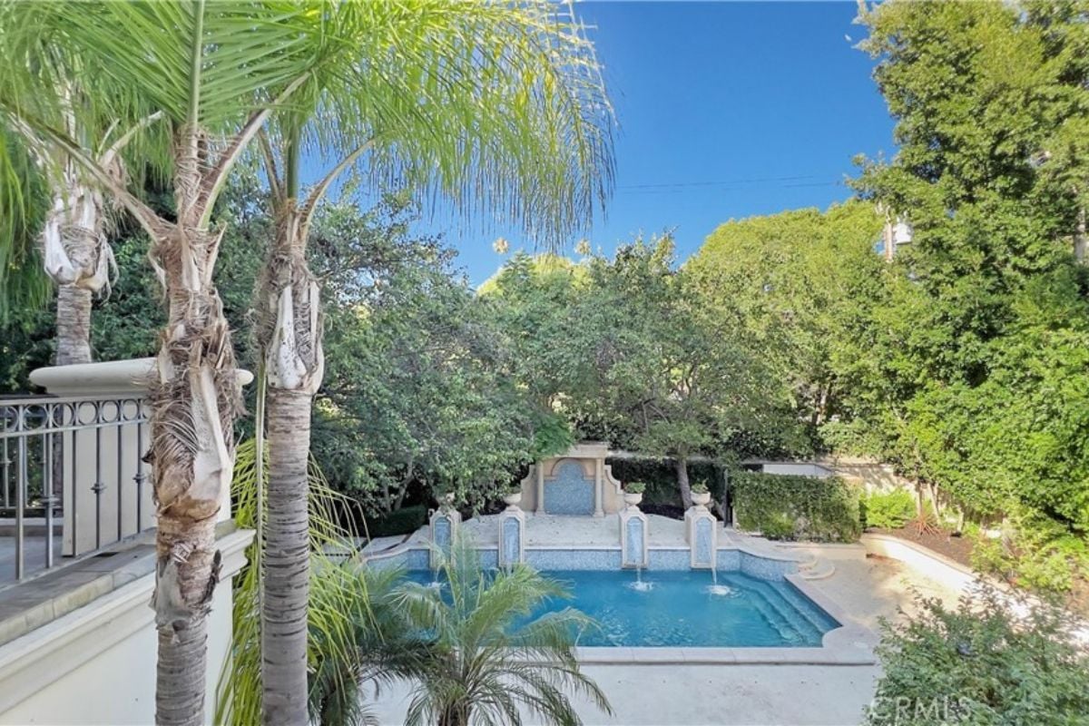A swimming pool with a jacuzzi, surrounded by plants and trees.