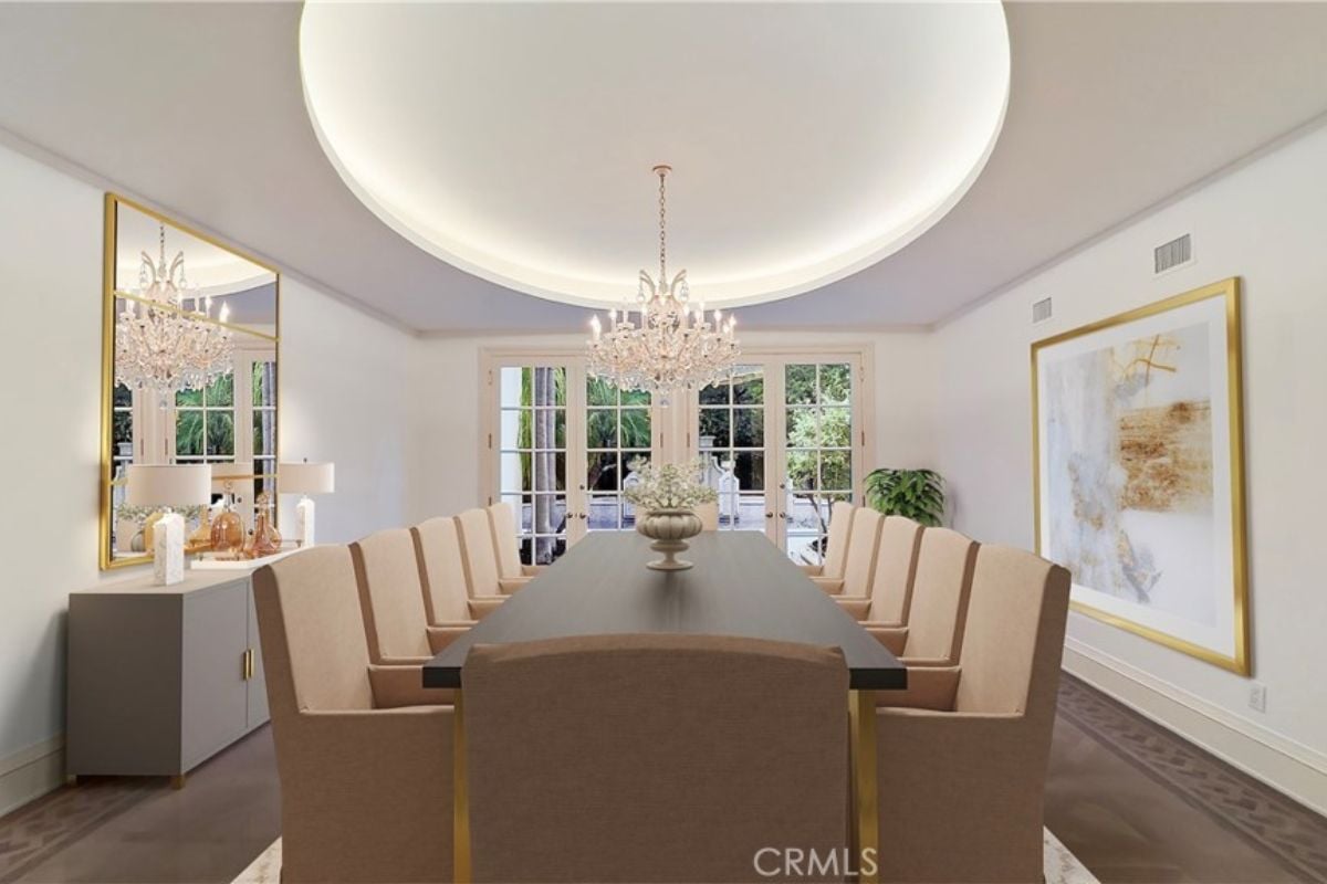 A dining room with a chandelier, a mirror, a painting, and a long table surrounded by chairs.