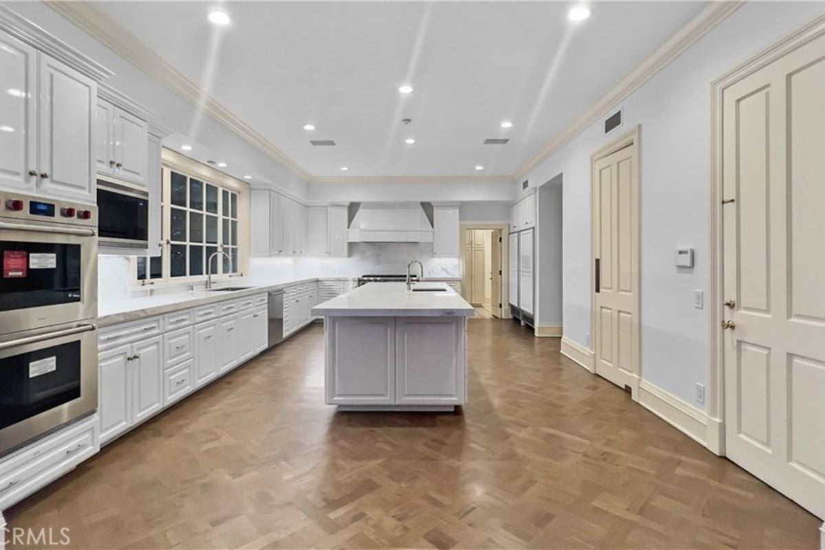 A kitchen with a center island, countertops, cabinets, a sink, and kitchen appliances.