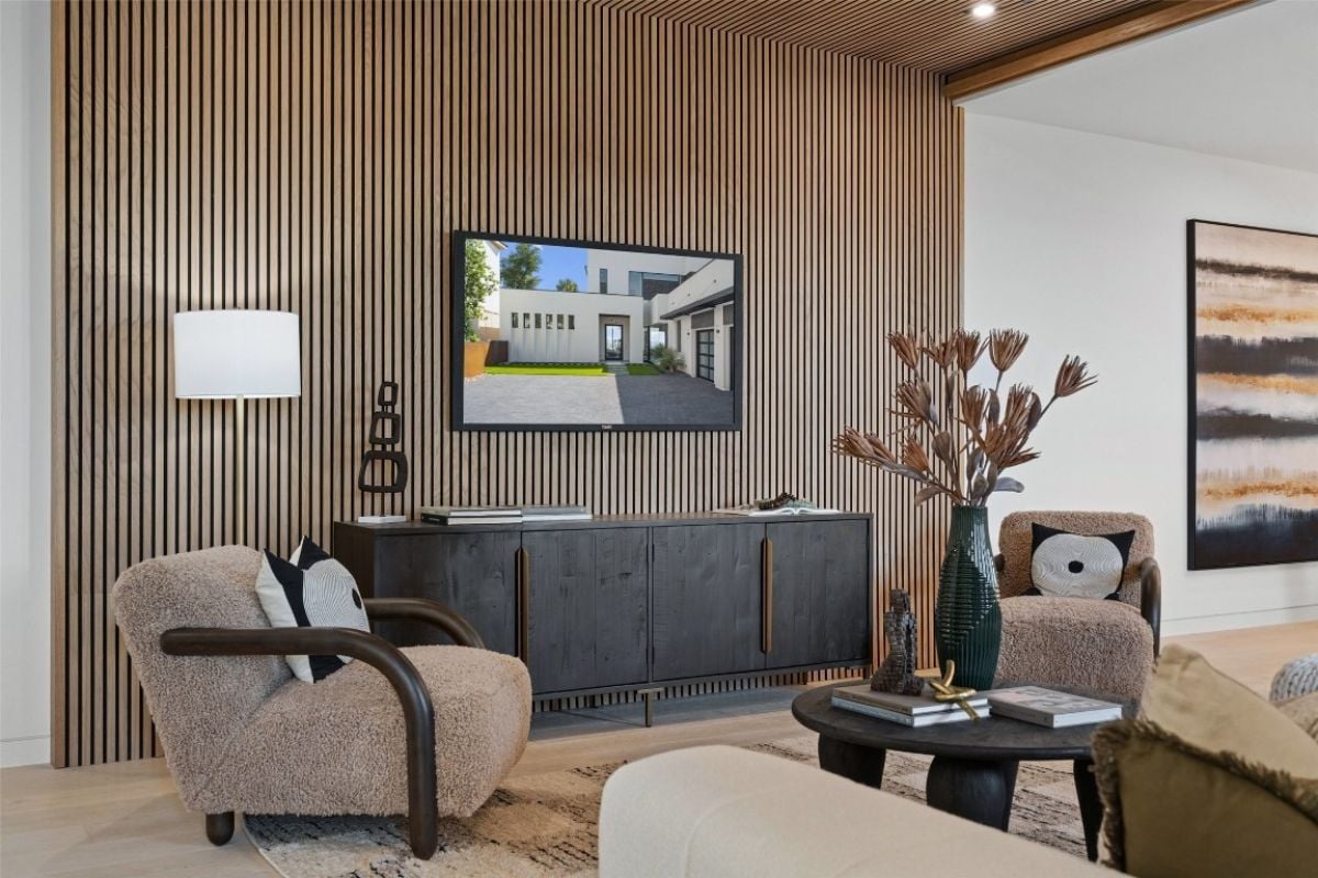 A family room with a TV, a cabinet, chairs, a rug, and a round center table with a vase on top.