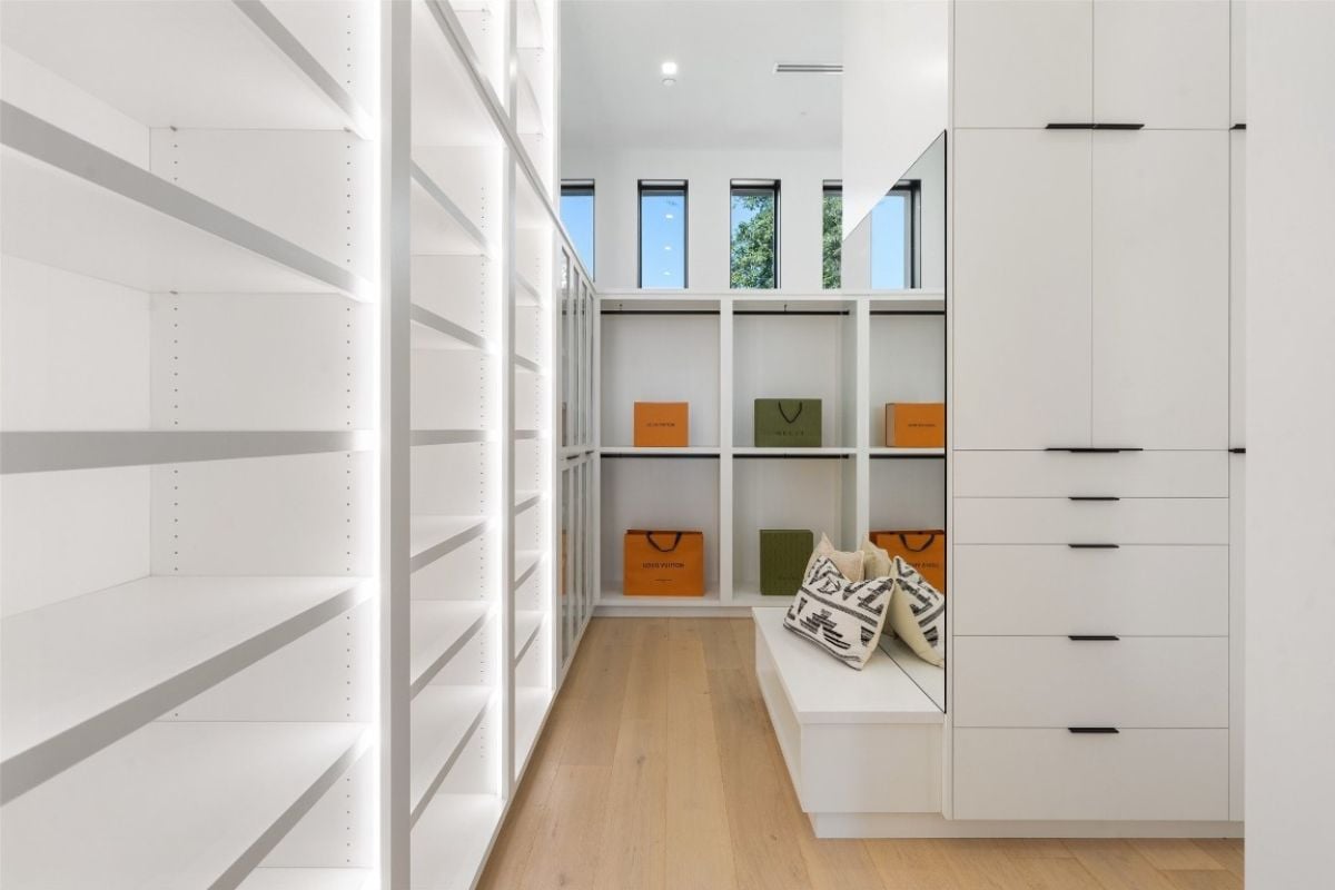 A walk-in closet with cabinets, a mirror, and a bench.