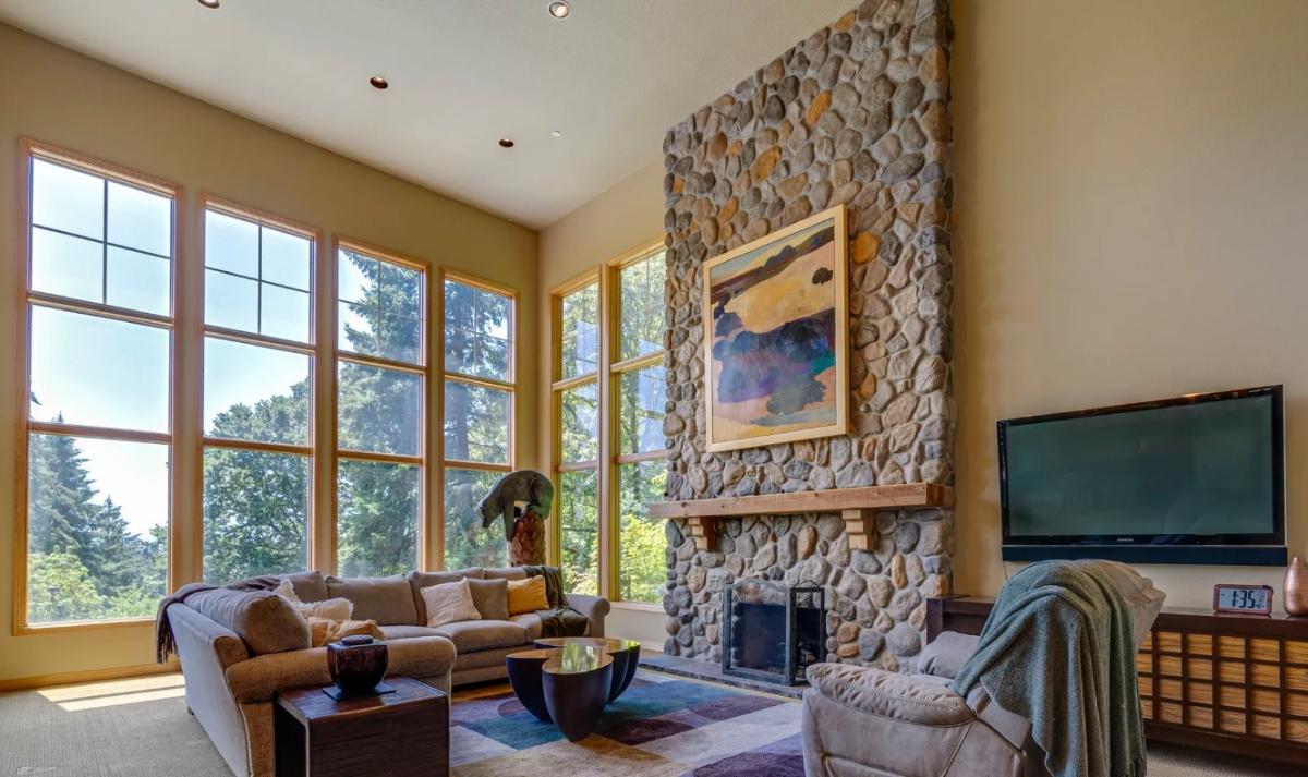 Living room with high ceilings, a fireplace and large glass windows.