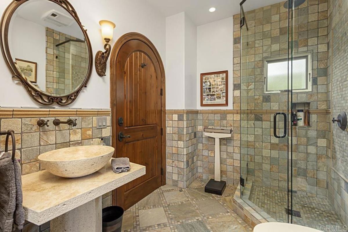 A bathroom with a vanity, mirror, and shower.