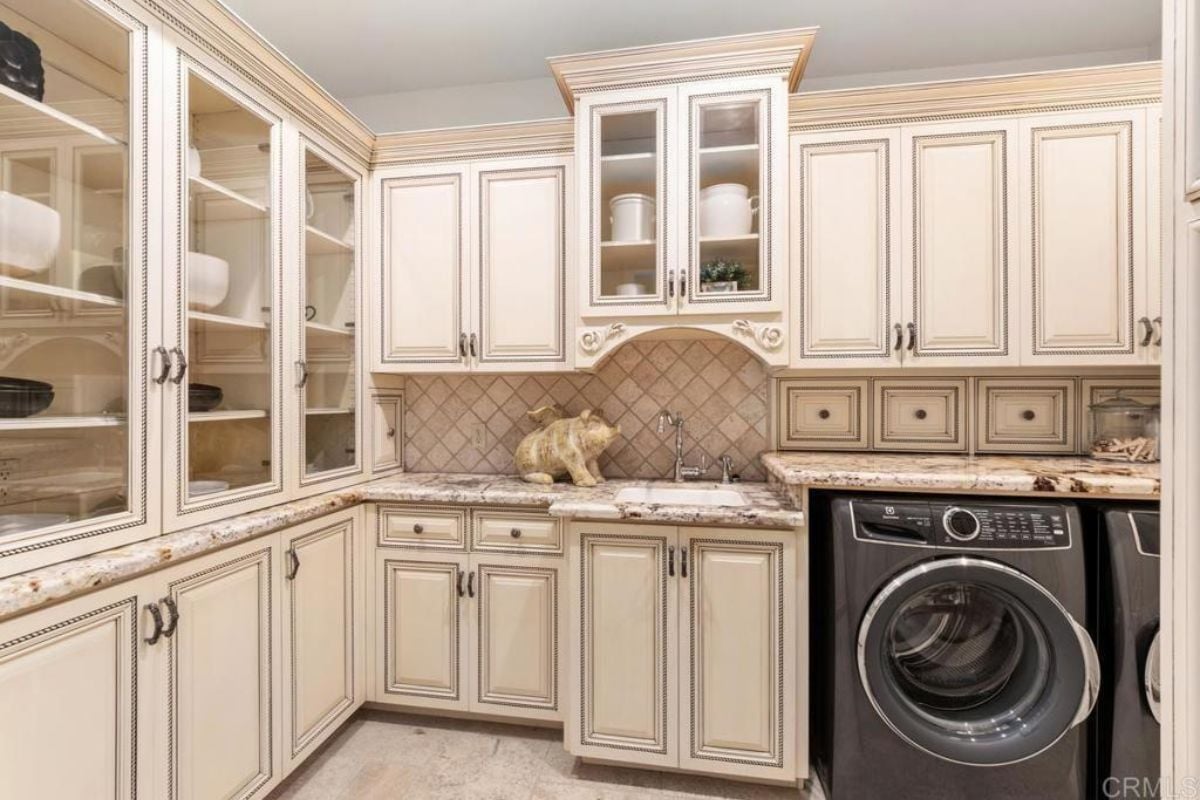 A laundry room with cabinets, a countertop, a sink, and washing machines.