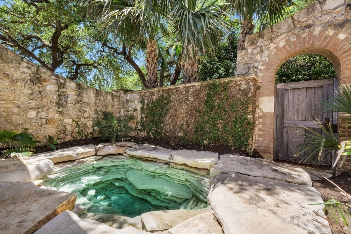 A swimming pool crafted with rocks and encircled by rock walls.