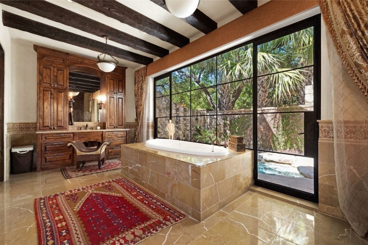 A bathroom with windows, a powder area, tall windows, and an exposed beam ceiling.