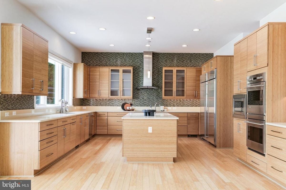A kitchen with a center island, countertops, cabinets, a sink, and kitchen appliances.