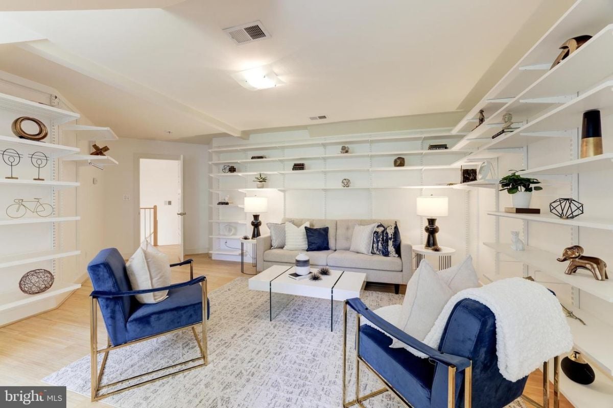A family room with shelves, a couch, chairs, and a coffee table.