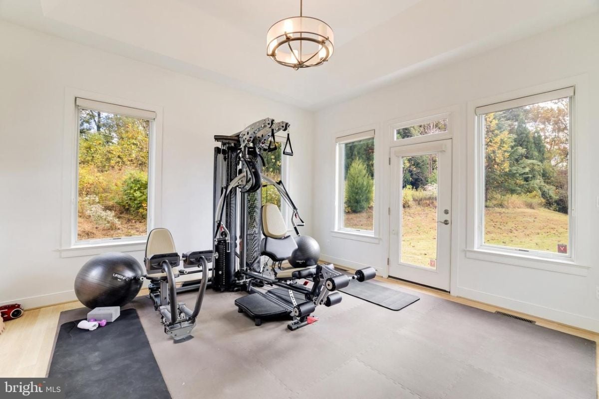 A home gym with windows and gym equipment.
